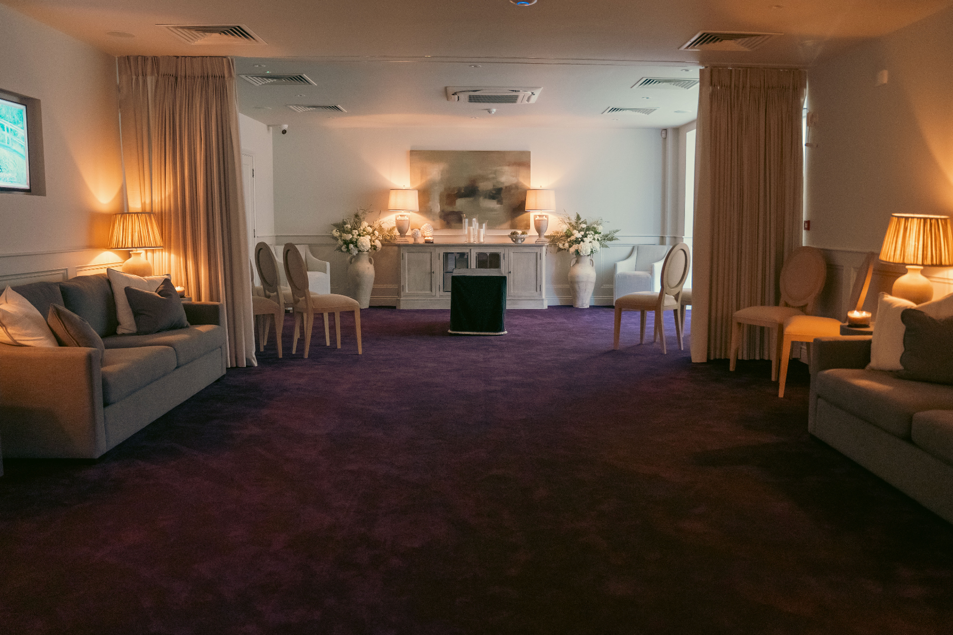 A wide repose room with soft lighting, flowers and comfortable seating
