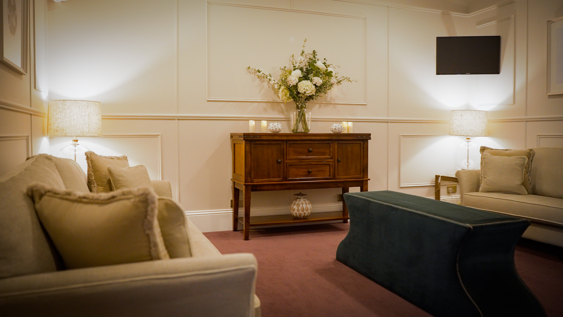 A carefully presented room with flowers, seating and dignified surroundings